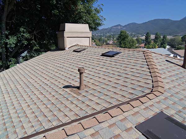 new light brown and gray asphalt roof shingle installation around skylights and ridge - view 2