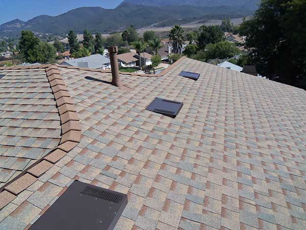new light brown and gray asphalt roof shingle installation around skylights and ridge - view 1