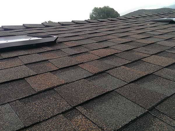 new brown asphalt roof shingle installation around skylights